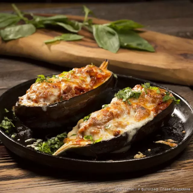 Лечо кошулган фарш менен толтурулуп бышырылган жана сыр жана райхон себилген баклажандар